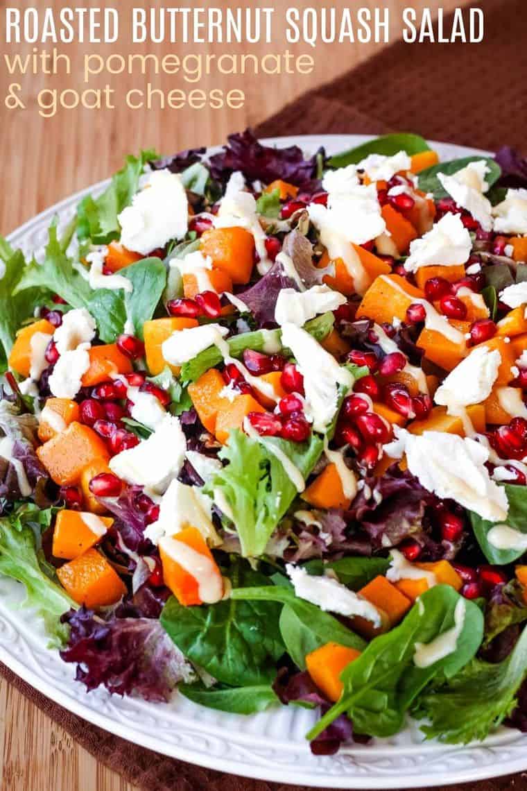 Salad topped with butternut squash, pomegranate seeds, crumbled blue cheese, and a creamy dressing