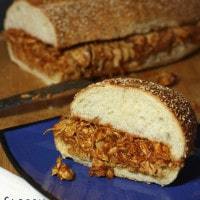 A barbecue chicken sandwich on a blue plate.