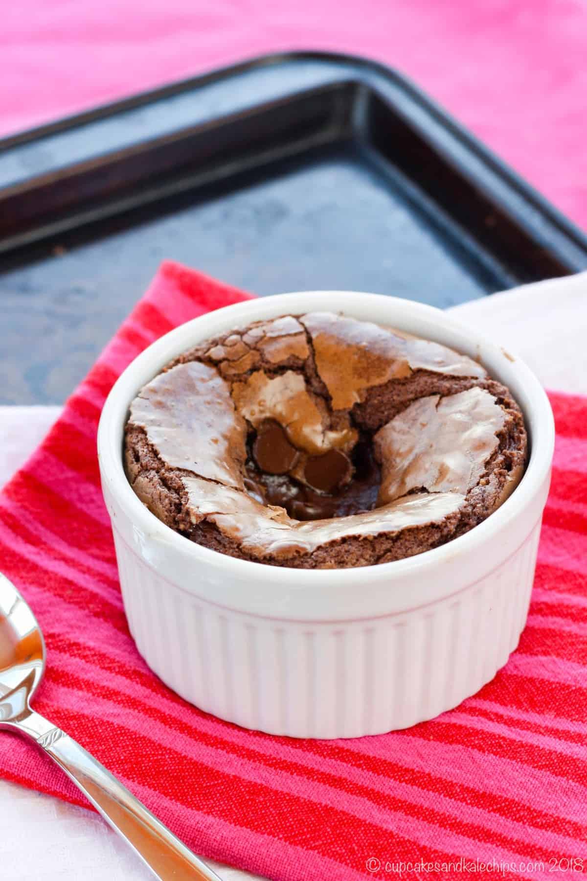 A brownie baked in a ramekin on top of red and white cloth napkins.