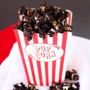 Chocolate popcorn in a red and white striped popcorn container.