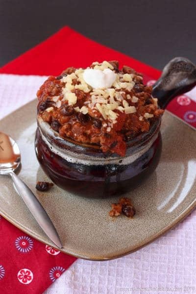 a crock of chili set on a plate.