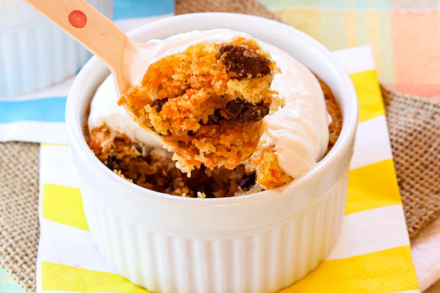 A bite of gluten free carrot cake held over the top of the carrot cake in a ramekin.