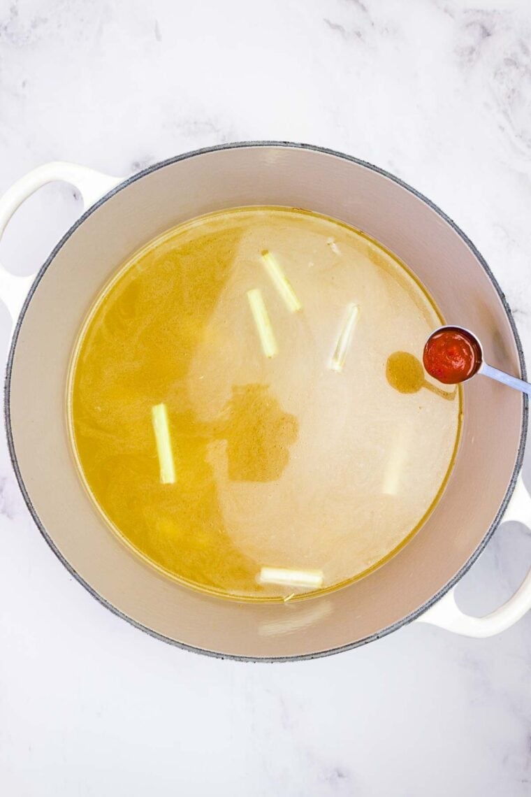 Adding sriracha sauce to broth