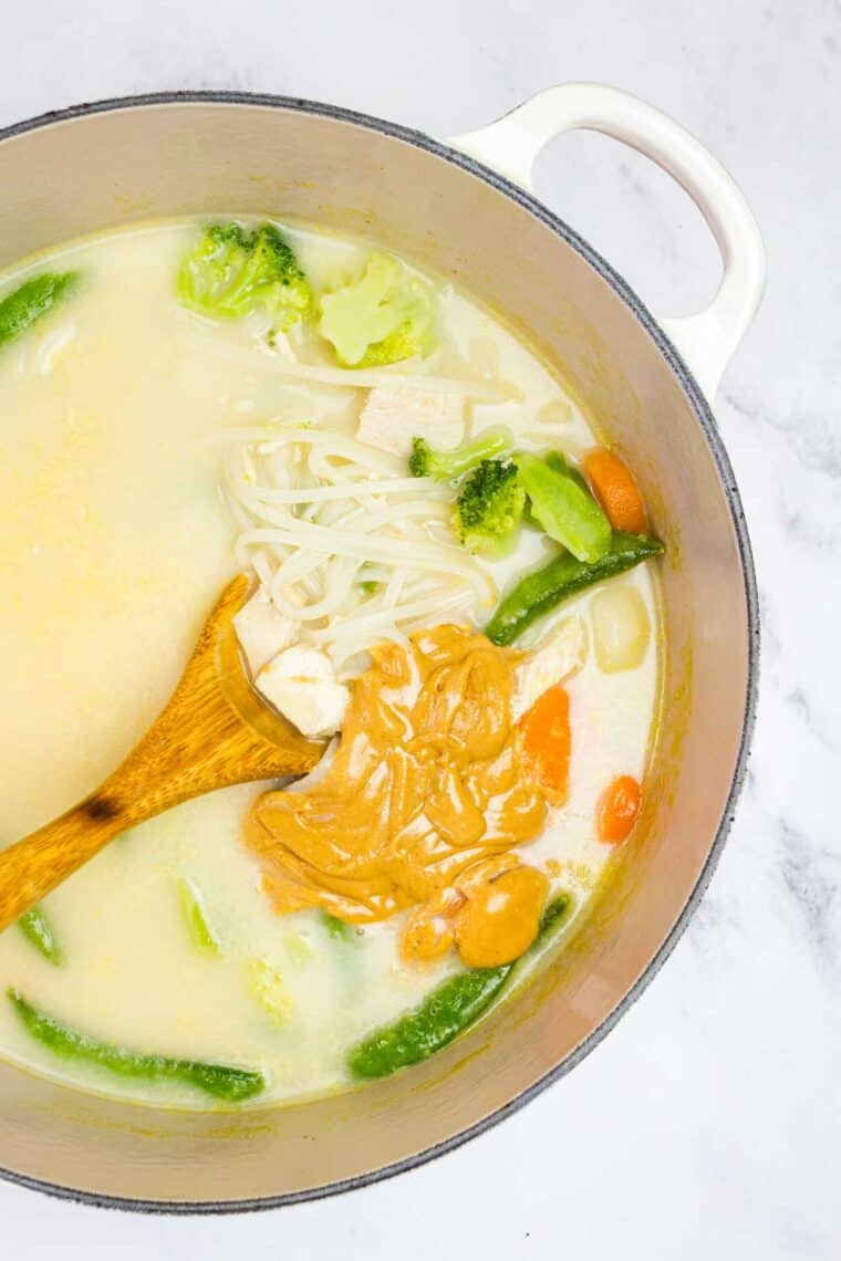 Stirring peanut butter into Thai chicken noodle soup