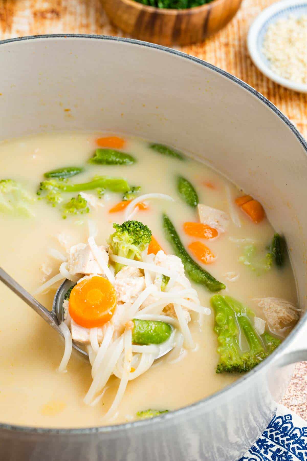 A spoon in a bowl of Thai chicken noodle soup