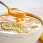 A spoon lifting creamy soup out of a bowl with text overlay that says "Thai Curry Butternut Squash Soup".