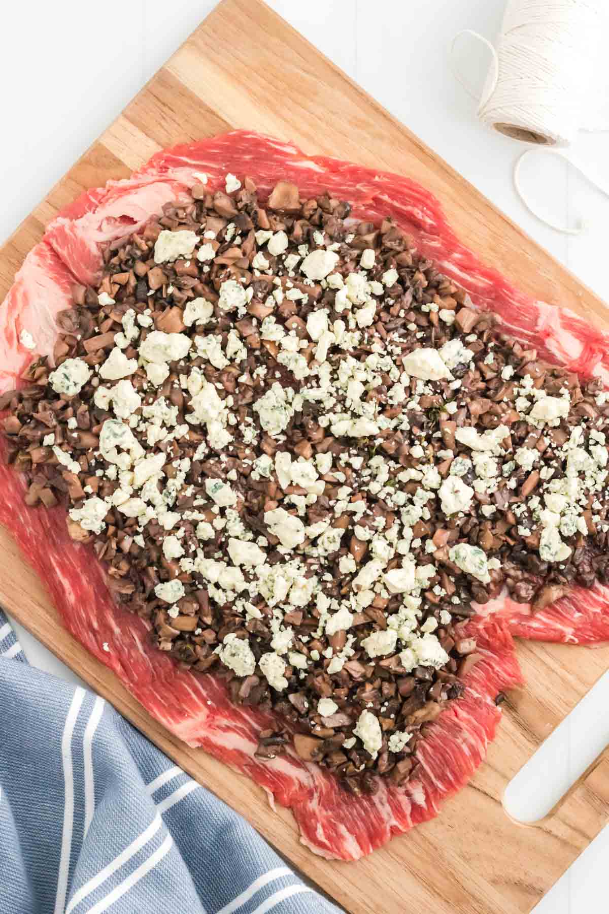 Gorgonzola cheese crumbled over mushroom duxelles, spread over a tenderized cut of flank steak.