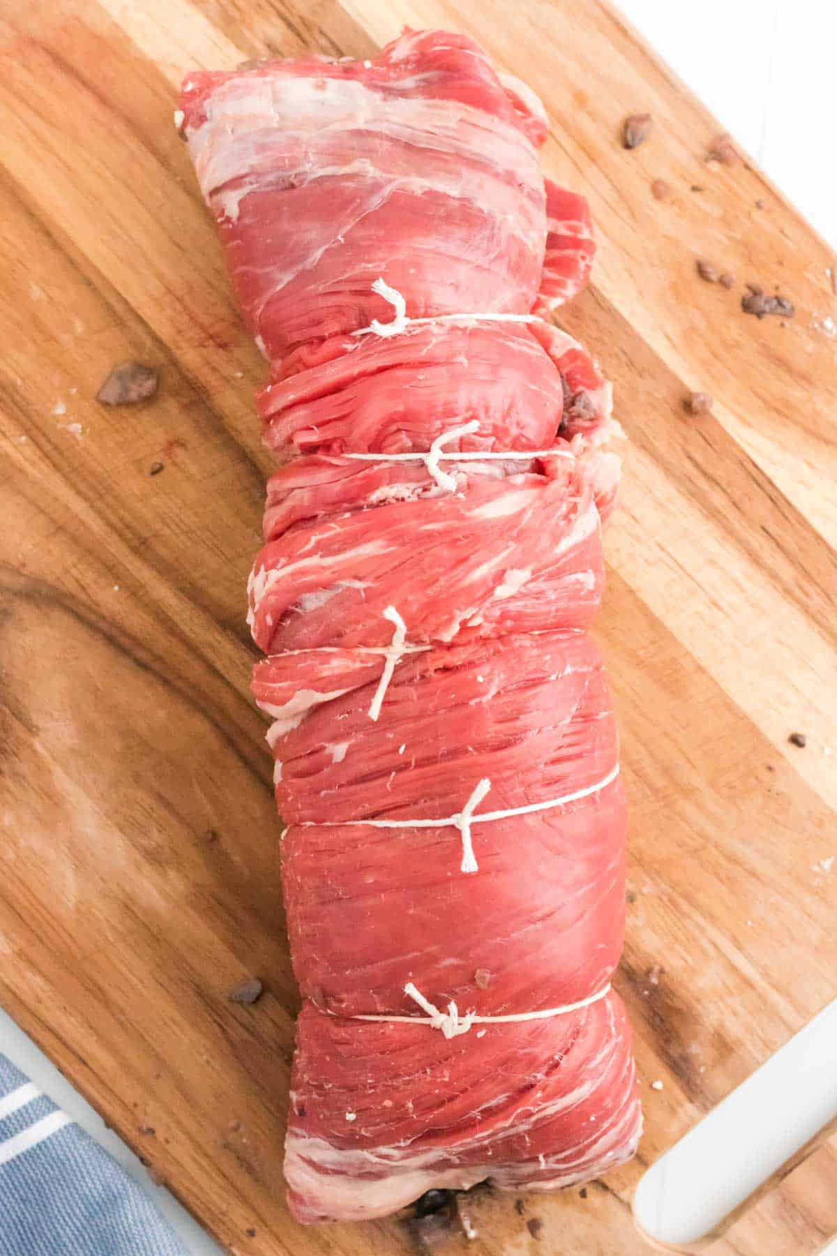 Rolled up flank steak stuffed with mushrooms, tied with twine.