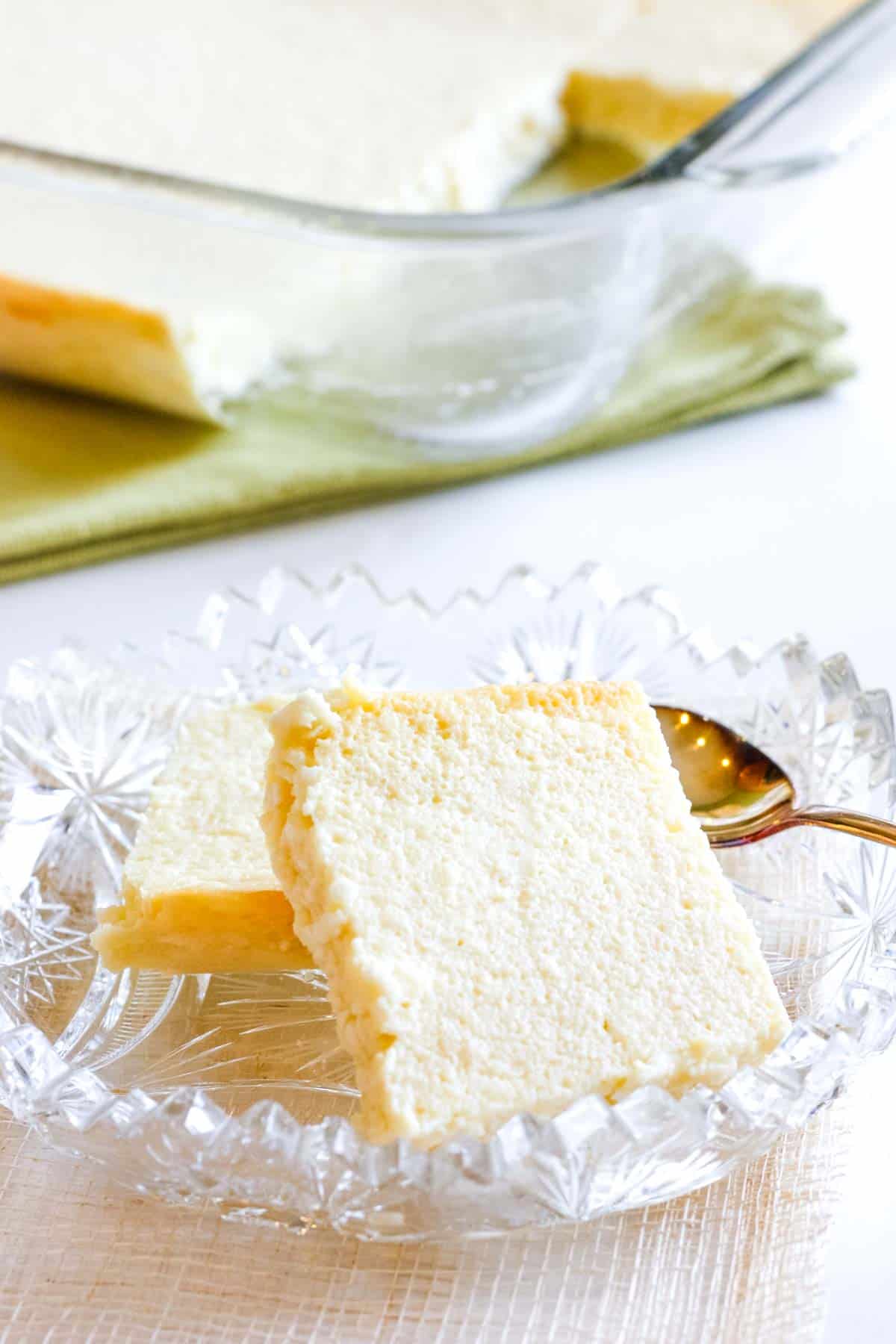 Two pieces of Ukrainian Easter cheese in a crustal dish with the rest of the cheese in a baking pan in the background.