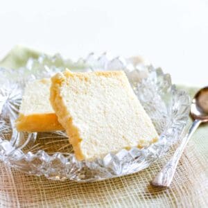 Two pieces of Syrnyk cheese in a crustal dish with a spoon lying next to it.