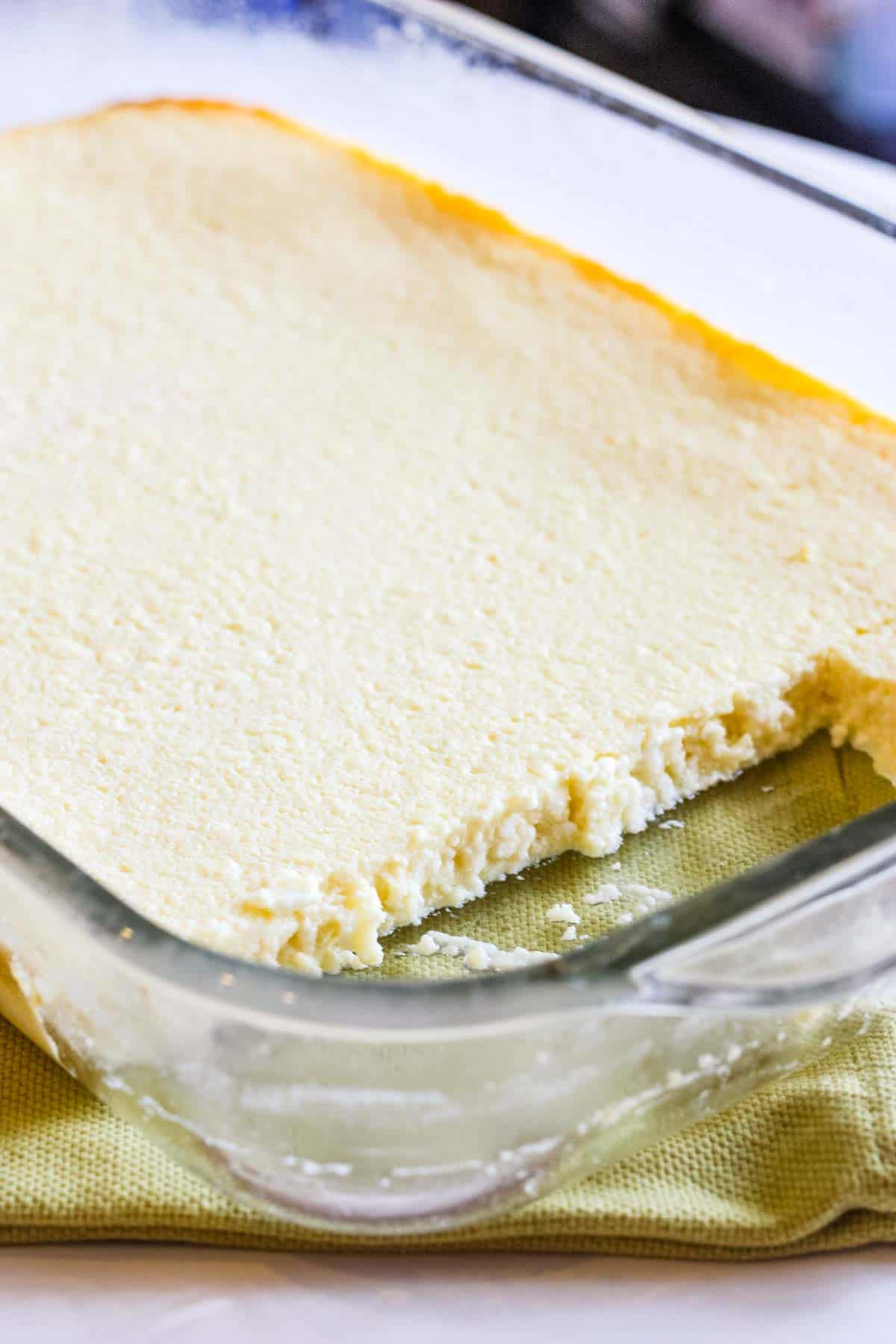 A glass baking dish of syrnyk sweet cheese with a few pieces removed.