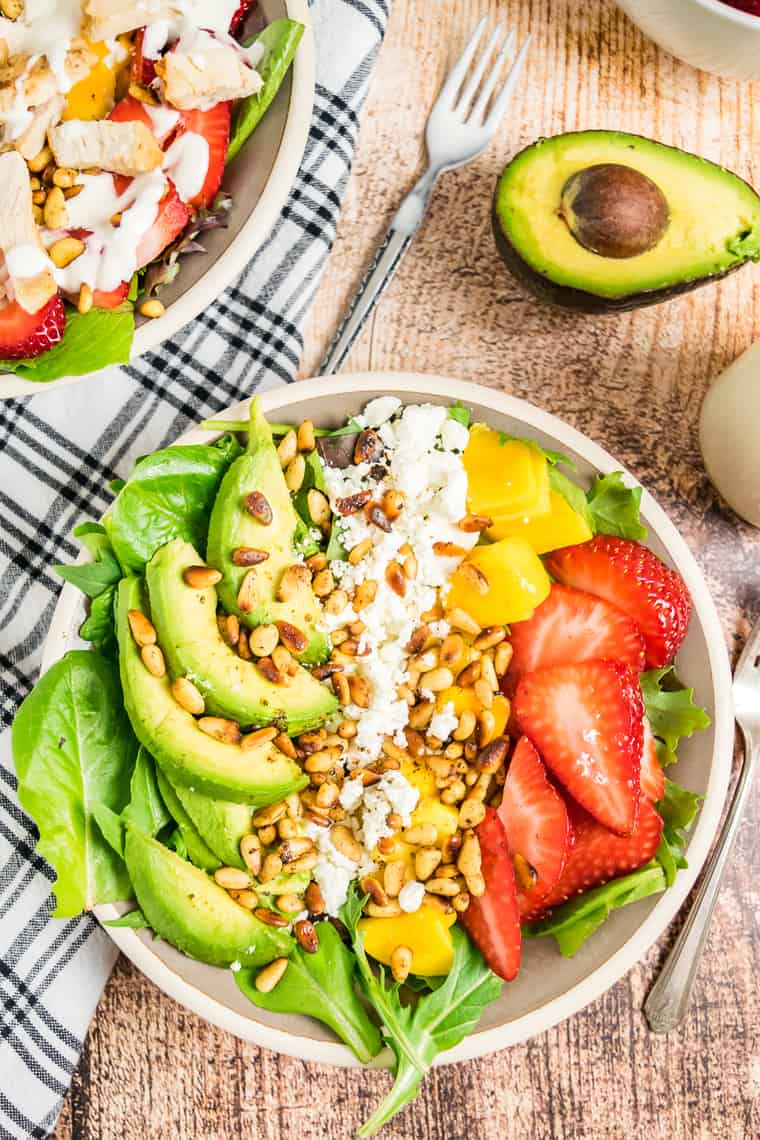 Overhead of Strawberry Mango Avocado Salad topped with goat cheese and toasted pine nuts