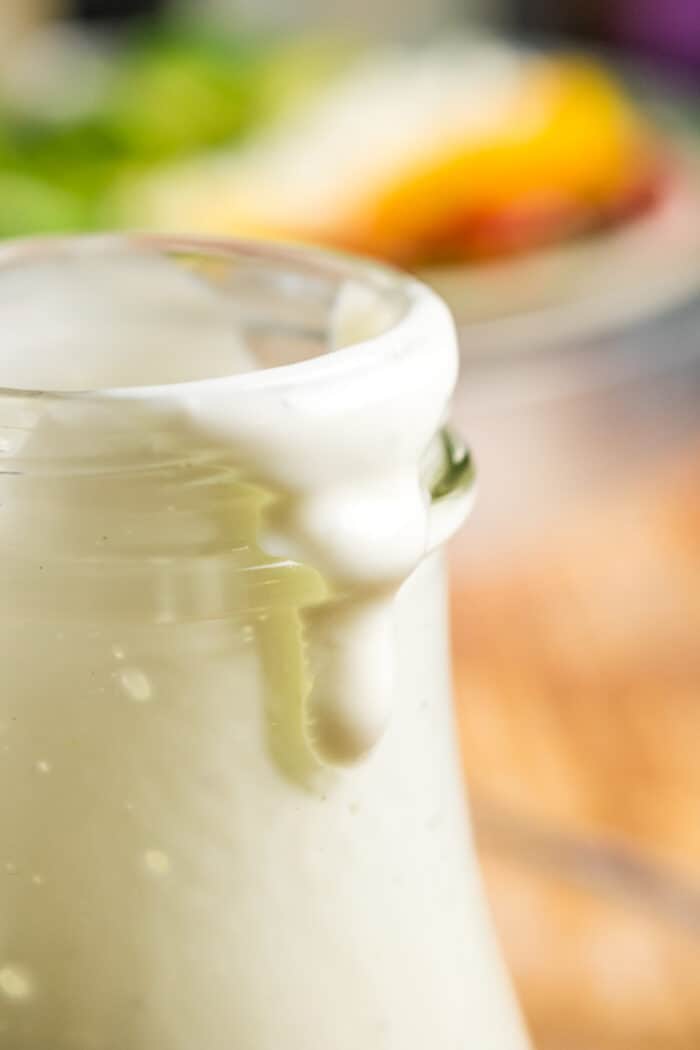 Lime Lemon Yogurt Dressing Dripping over the edge of a bottle