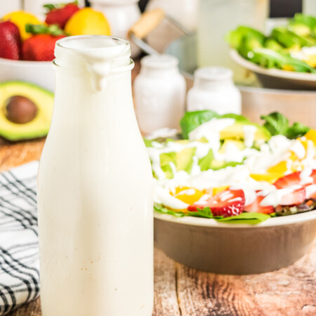 Creamy Greek Yogurt Honey Lemon-Lime Dressing in a bottle with a salad in the background