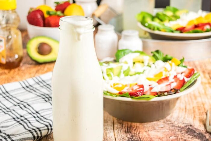 Creamy Greek Yogurt Honey Lemon-Lime Dressing in a bottle with a salad in the background