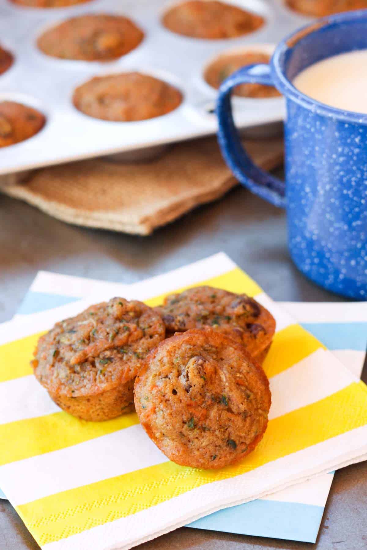 three muffins on a stack of two colored napkins in front of a mini muffin tin