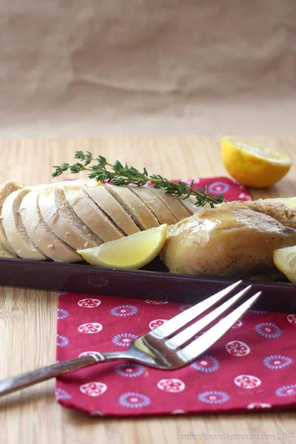 Lemon Herb Crock Pot Roast Chicken sliced on a serving platter with a fork in front