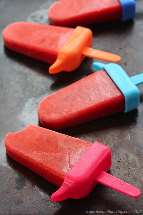 Mango Strawberry Ice Pops laying on a dark sheet pan