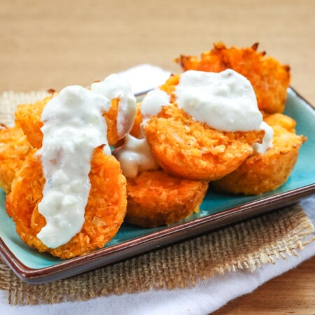 Buffalo cauliflower tots on a small rectangular plate with blue cheese dressing dripping over them