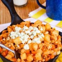 Spicy breakfast hash topped with blue cheese in a cast iron pan