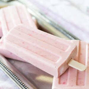Several strawberry yogurt popsicles scattered on a pewter platter.