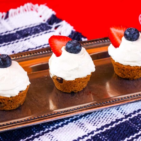 Three Cheesecake Chocolate Chip Cookie Cups topped with berries on a rectangular silver platter