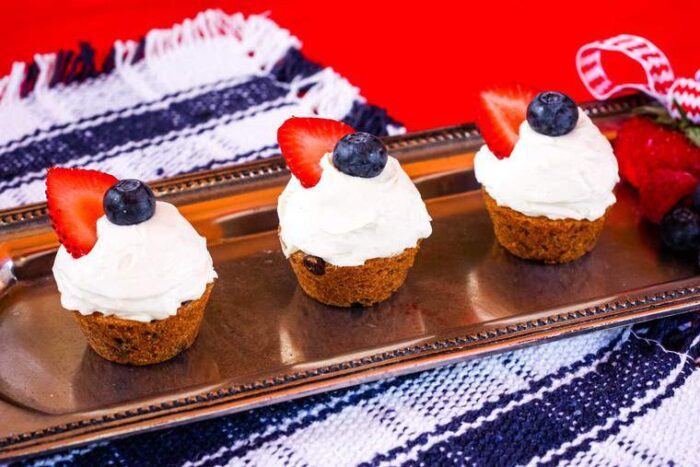 Three Cheesecake Chocolate Chip Cookie Cups topped with berries on a rectangular silver platter