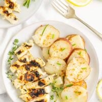 Grilled chicken dinner on a plate with cooked potato slices