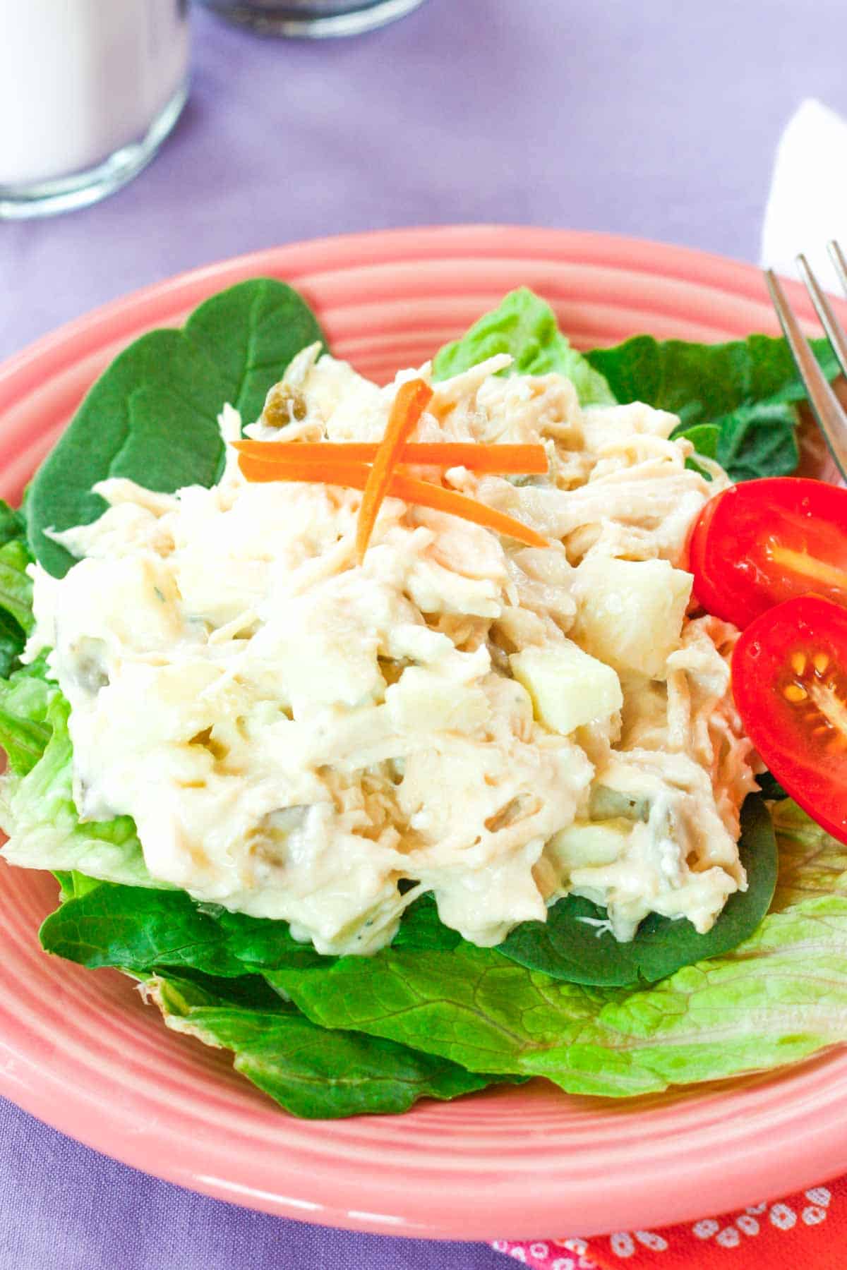 A plate of lettuce topped with chicken salad.