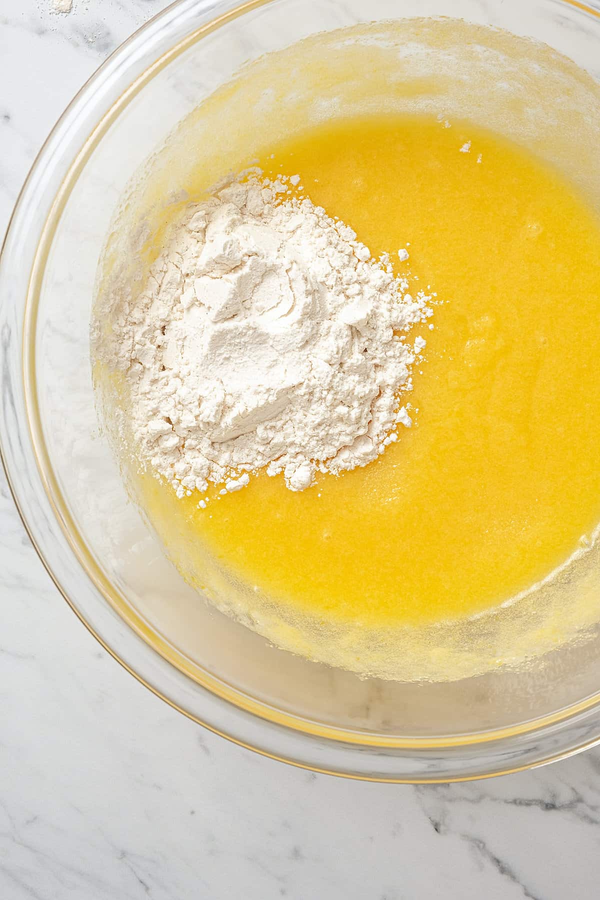 Dry ingredients are added into a glass bowl with the wet ingredients for cookie pie.