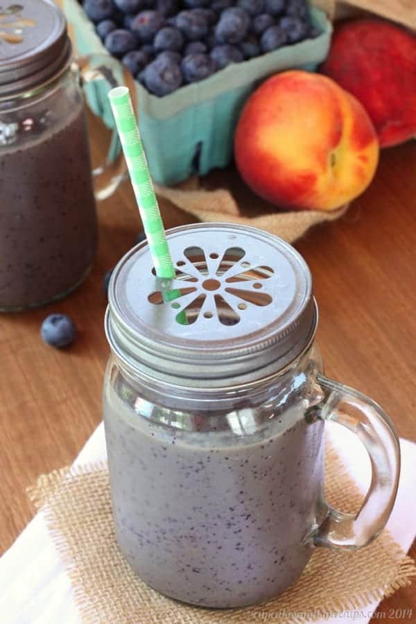 A Blueberry and Peach Green Smoothie in a sipping cup with a straw.