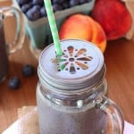 A Blueberry and Peach Green Smoothie in a sipping cup with a straw.