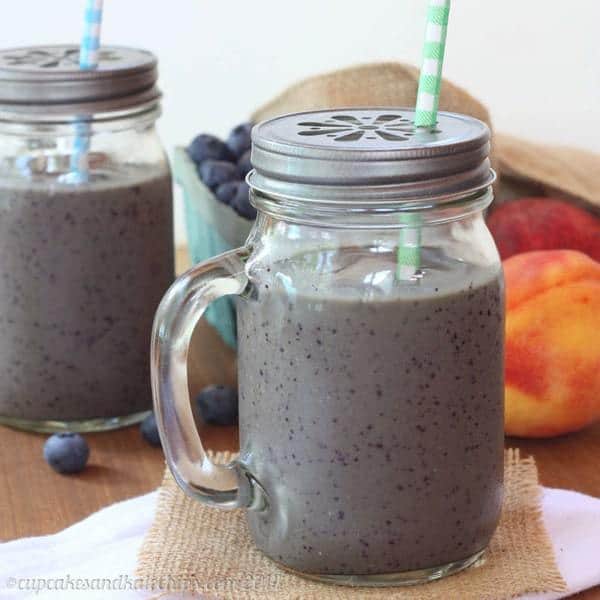 Blueberry and Peach Green Smoothies in sipping cups with straws.