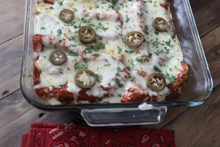 Cheesy breakfast enchiladas in a casserole dish topped with jalapeno slices.