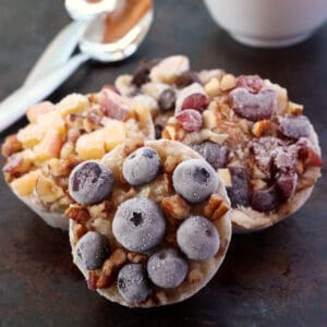 Four frozen Breakfast Oatmeal Cups topped with fruit on a sheet pan.