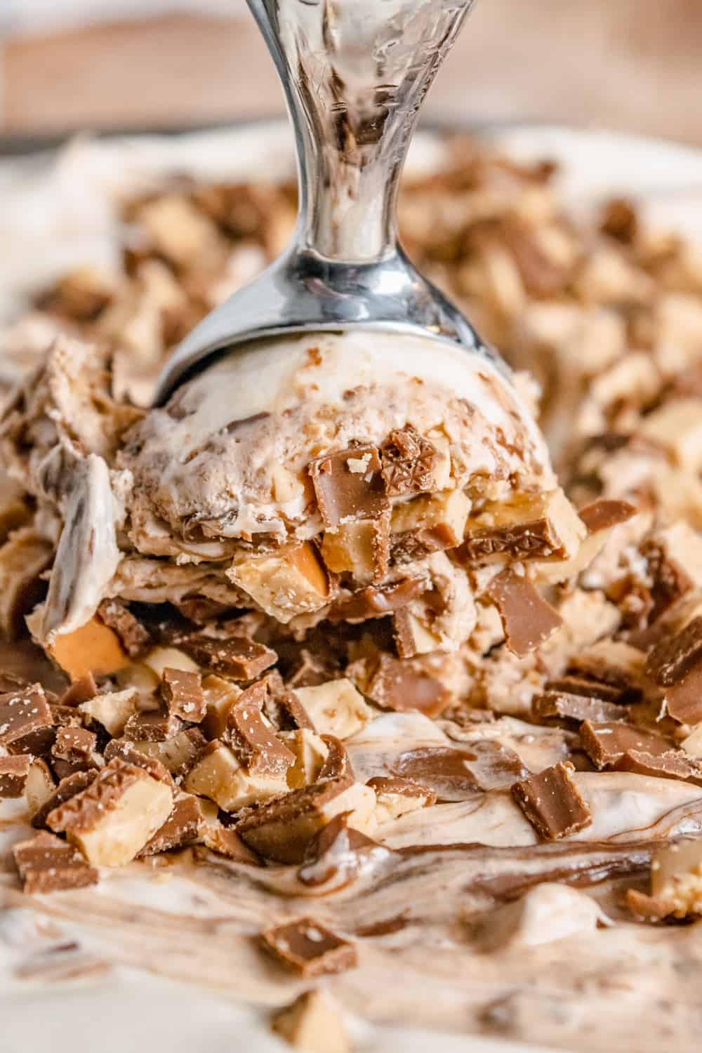 Closeup of a scoop in a container of Toffee Nutella Ice Cream covered in Heath bits.
