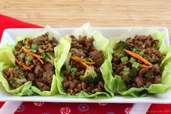 Three Asian beef and broccoli lettuce wraps on a rectangular plate.