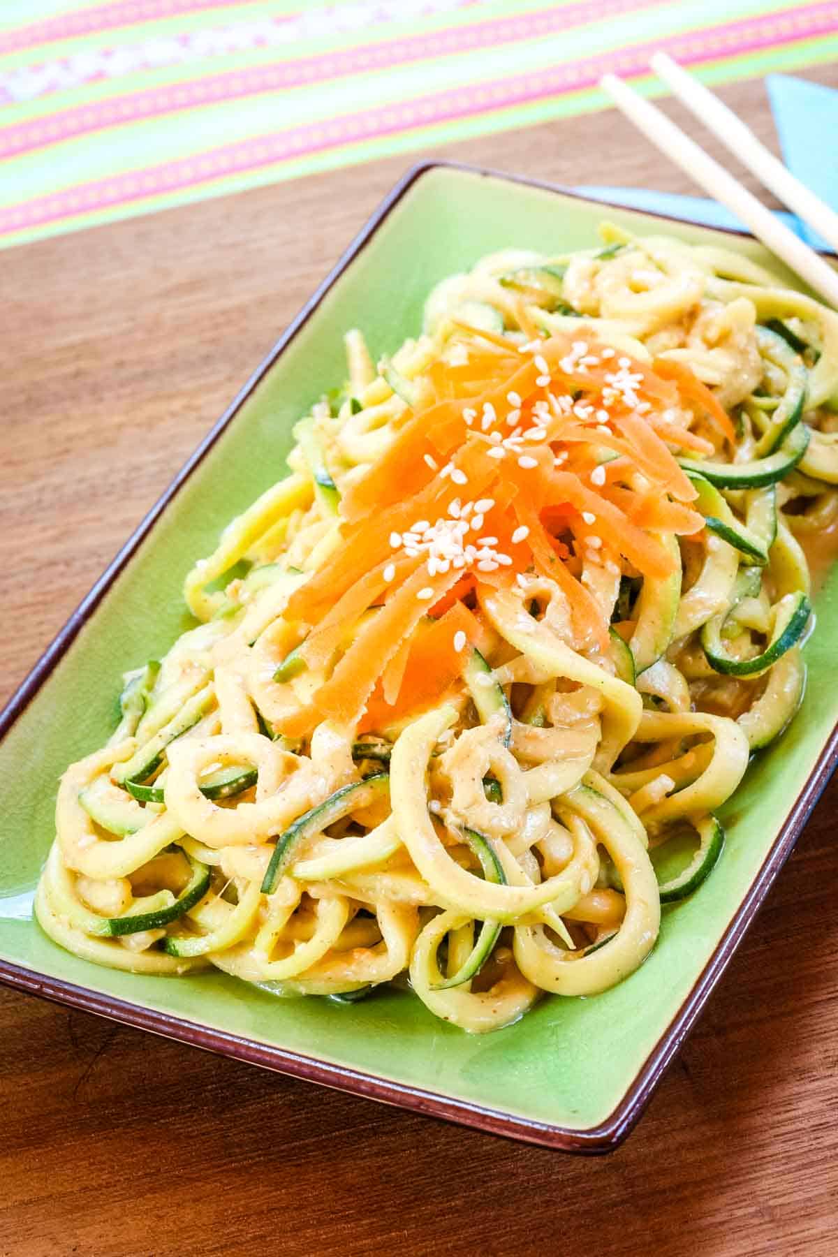 A plate of cold Sesame Zucchini Noodles Salad Recipe on top of a wooden board.