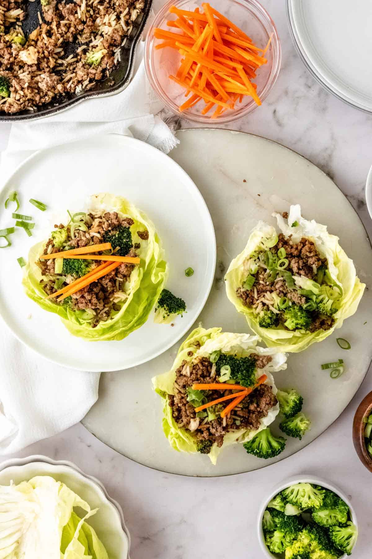 Overhead view of three assembled Asian lettuce wraps surrounded by wrap ingredients.