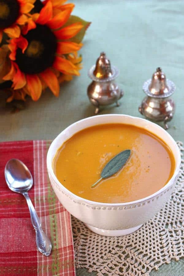 Apple Cider and Cheddar Cheese Butternut Squash Soup in a white bowl with a silver spoon