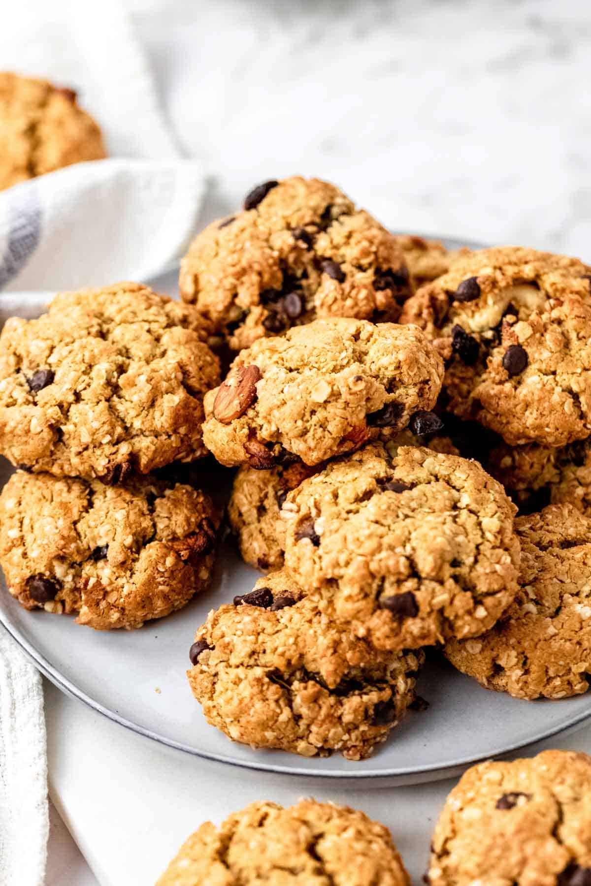 Assorted gluten-free trail mix cookies piled on a grey plate, on a white marble countertop.