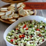 layered greek humus dip in a white ceramic dish