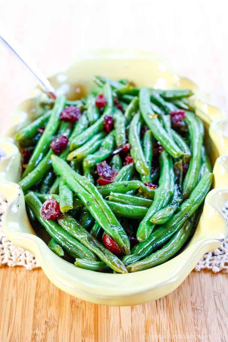 Easy green beans recipe with dried cranberries and orange glaze in a yellow serving dish