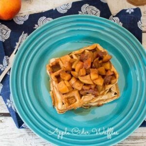 Apple cider waffles topped with caramelized apples on a blue plate.