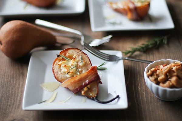 Bacon wrapped pear half with goat cheese on a square plate