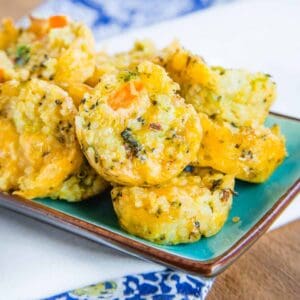 Cheesy Veggie Quinoa Bites on a small turquoise dish on top of blue and white napkins.
