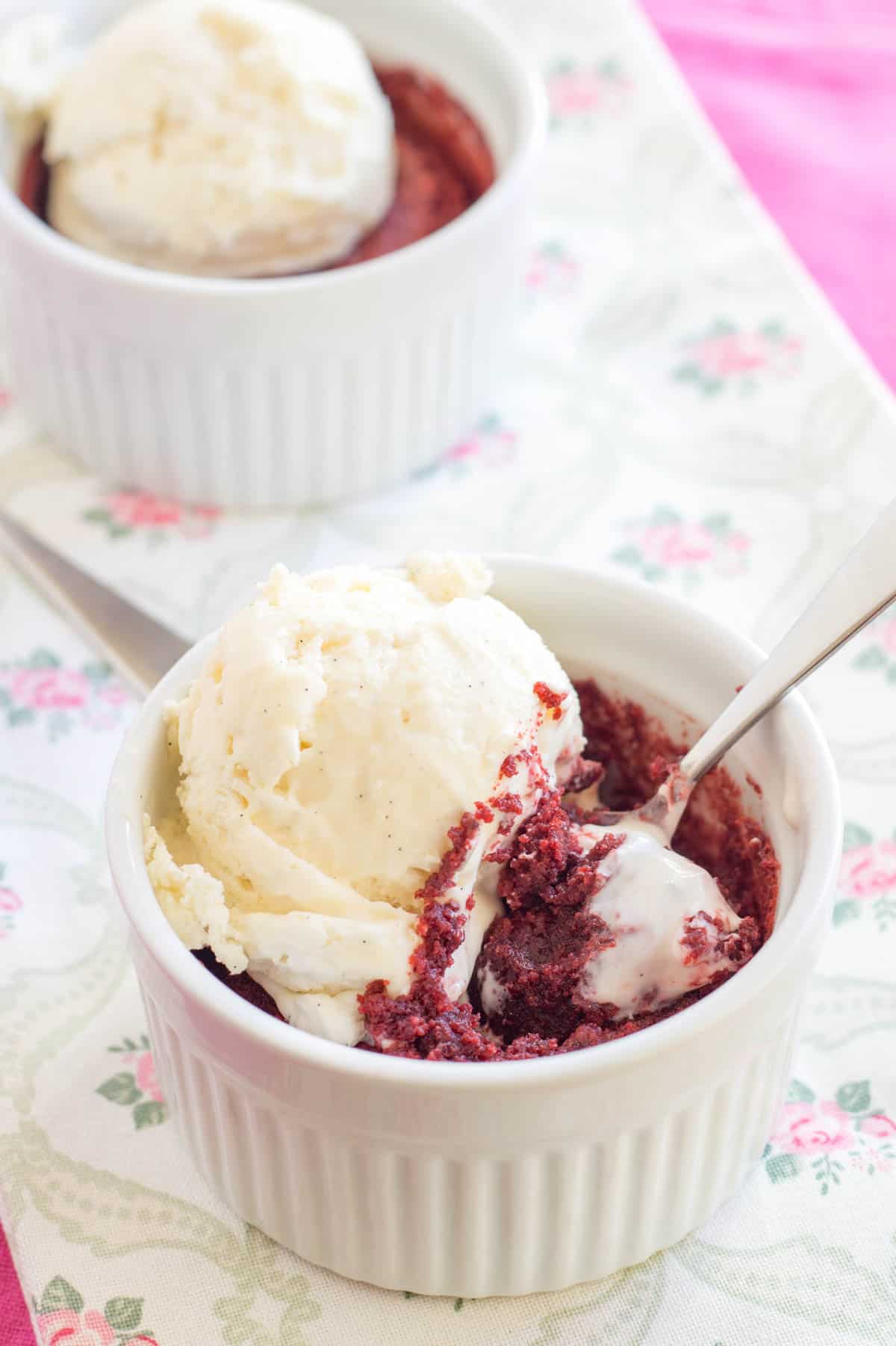 A red velvet brownie baked in a ramekin topped with a scoop of ice cream.