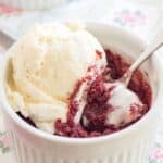 A brownie in a ramekin topped with a scoop of vanilla ice cream with text overlay that says "Gluten Free Red Velvet Mug Brownies for Two".