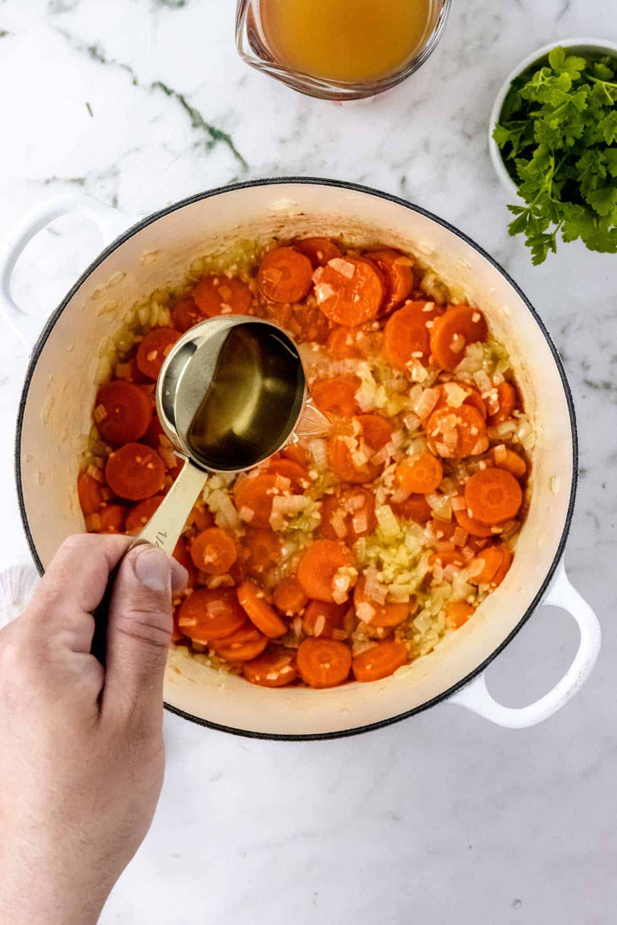A half cup of white wine is added to a pot of sauteed veggies.