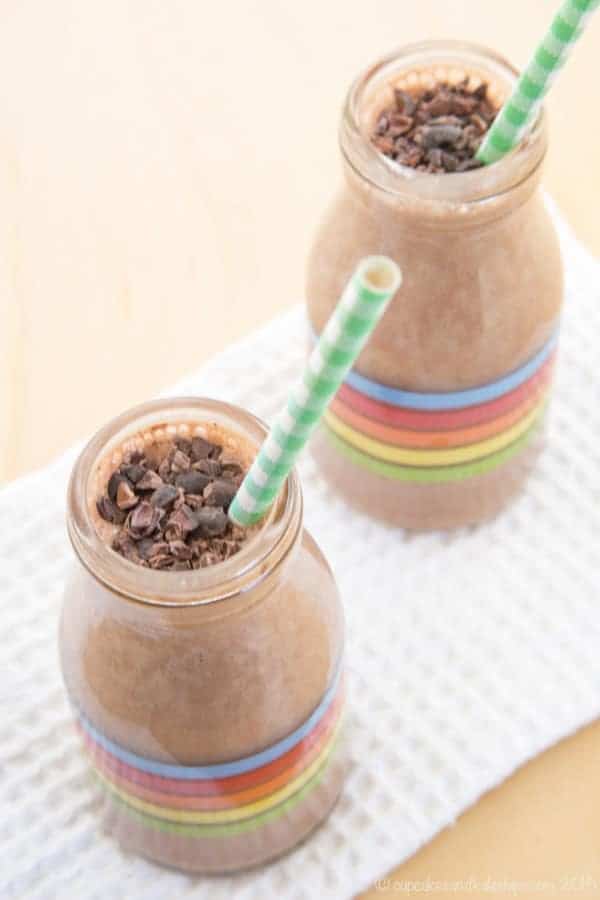 Two mint chocolate smoothies in glass bottles with rainbow stripes